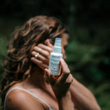 La photo montre une femme vaporisant un produit sur sa peau dans un environnement naturel. La composition transmet une sensation de fraîcheur et de bien-être, parfaite pour illustrer l’utilisation de produits naturels ou de soins de beauté, comme des hydrolats ou des brumes florales, en harmonie avec la nature. Ce type de visuel pourrait être utilisé pour valoriser les bienfaits de produits à base de plantes, soulignant un rituel de soin délicat et apaisant en pleine nature.
Femme vaporisant un spray sur s