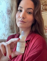 magnifique femme montrant le produit elixir de beauté de BELLE LUCE cosmétiques flacon premium en verre opale avec étiquette raffinée EDELWEISS 