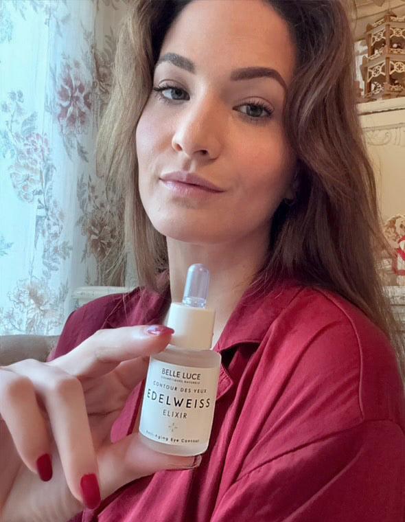 magnifique femme montrant le produit elixir de beauté de BELLE LUCE cosmétiques flacon premium en verre opale avec étiquette raffinée EDELWEISS 