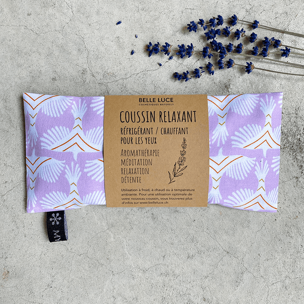 Coussin relaxant pour les yeux de la marque Belle Luce, au motif violet et orange avec des motifs géométriques. Ce coussin est utilisé pour la relaxation, l'aromathérapie et la méditation, offrant des options réfrigérantes ou chauffantes. L'emballage met en avant ses bienfaits de détente. Des brins de lavande sont posés à côté, soulignant le lien avec l'aromathérapie