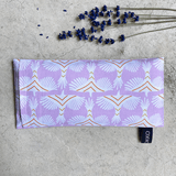 Coussin relaxant pour les yeux de la marque Belle Luce, au motif violet et orange avec des motifs géométriques. Ce coussin est utilisé pour la relaxation, l'aromathérapie et la méditation, offrant des options réfrigérantes ou chauffantes. L'emballage met en avant ses bienfaits de détente. Des brins de lavande sont posés à côté, soulignant le lien avec l'aromathérapie